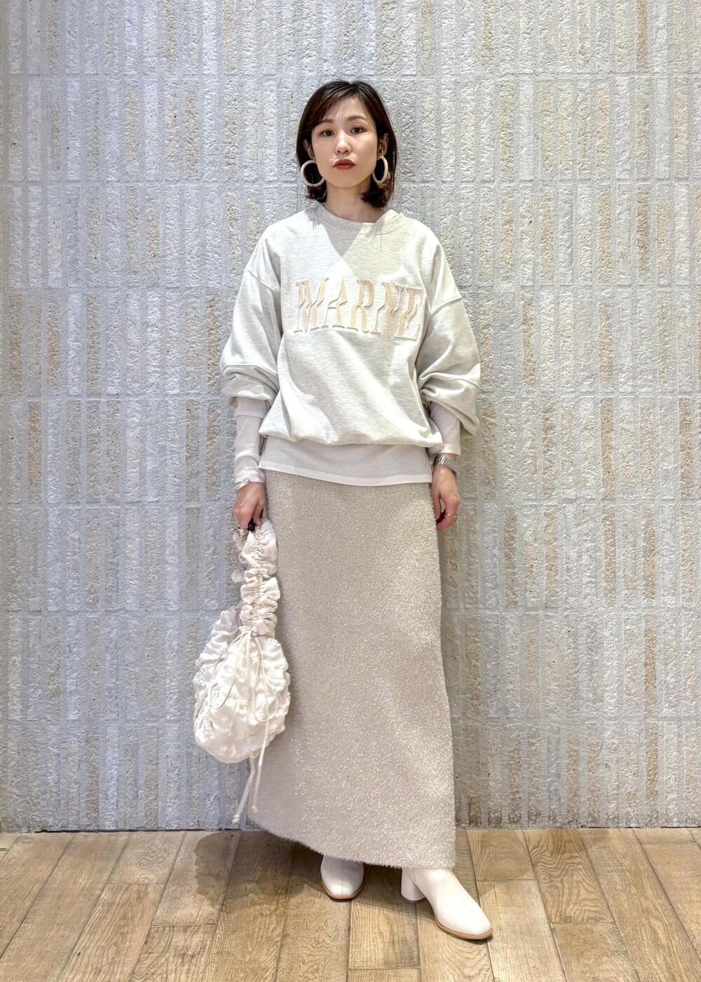 ホワイト系のブーツ、ベージュ系のスカート、ホワイト系のTシャツ/カットソーを着用したレディースの冬コーディネートの9枚目の写真
