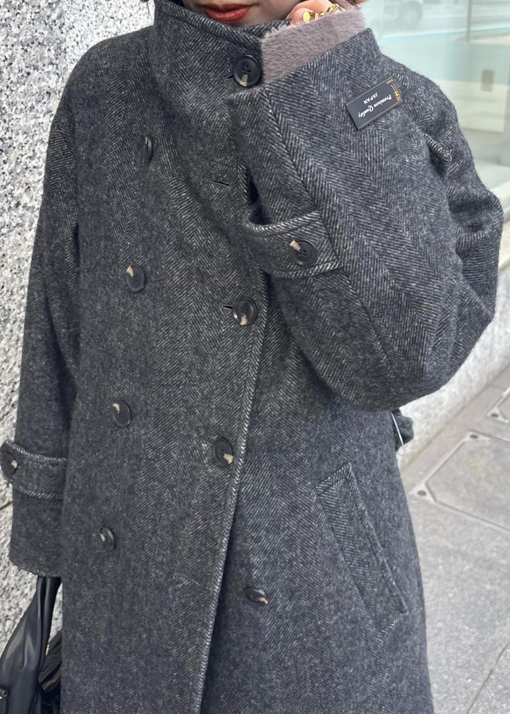 ブルー系のデニムパンツ、ブラック系のブーツ、ブラック系のハンドバッグを着用したレディースの秋コーディネートの2枚目の写真