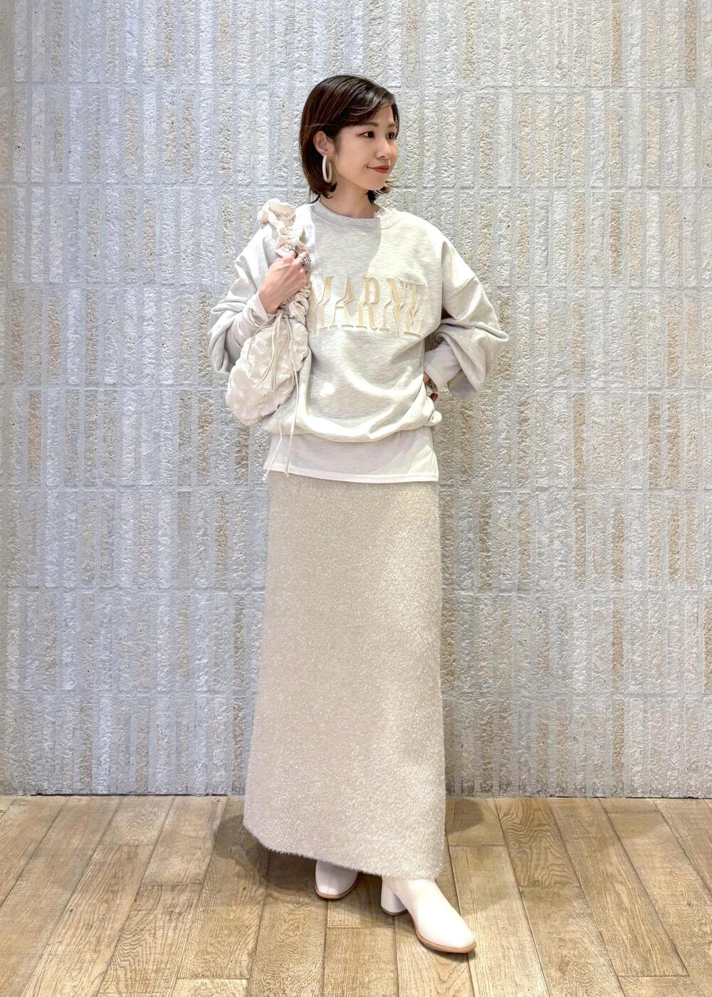 ホワイト系のブーツ、ベージュ系のスカート、ホワイト系のTシャツ/カットソーを着用したレディースの冬コーディネートの10枚目の写真