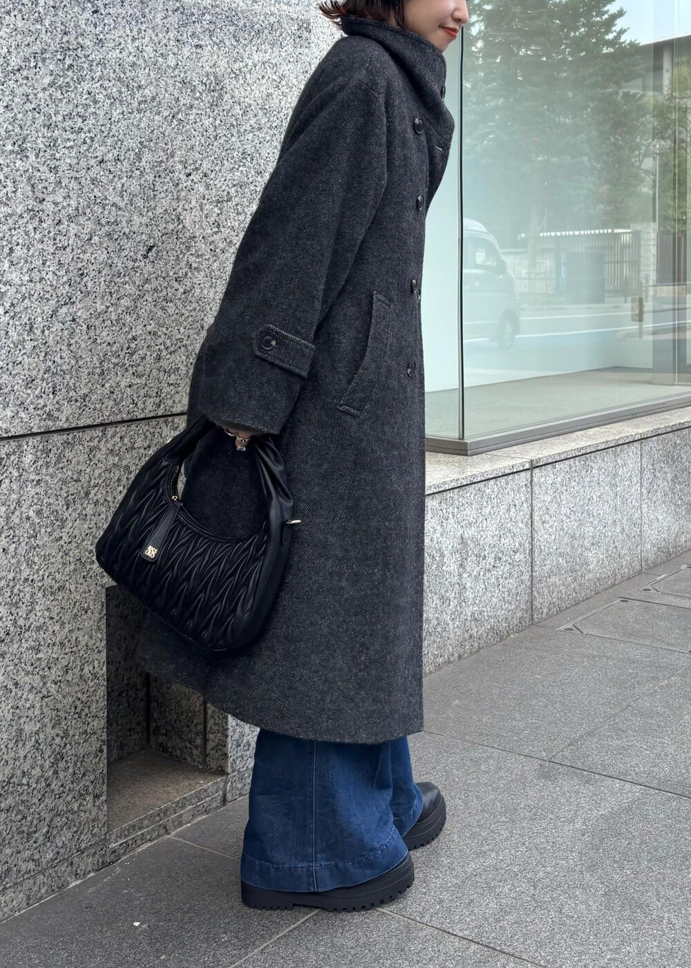 ブルー系のデニムパンツ、ブラック系のブーツ、ブラック系のハンドバッグを着用したレディースの秋コーディネートの6枚目の写真