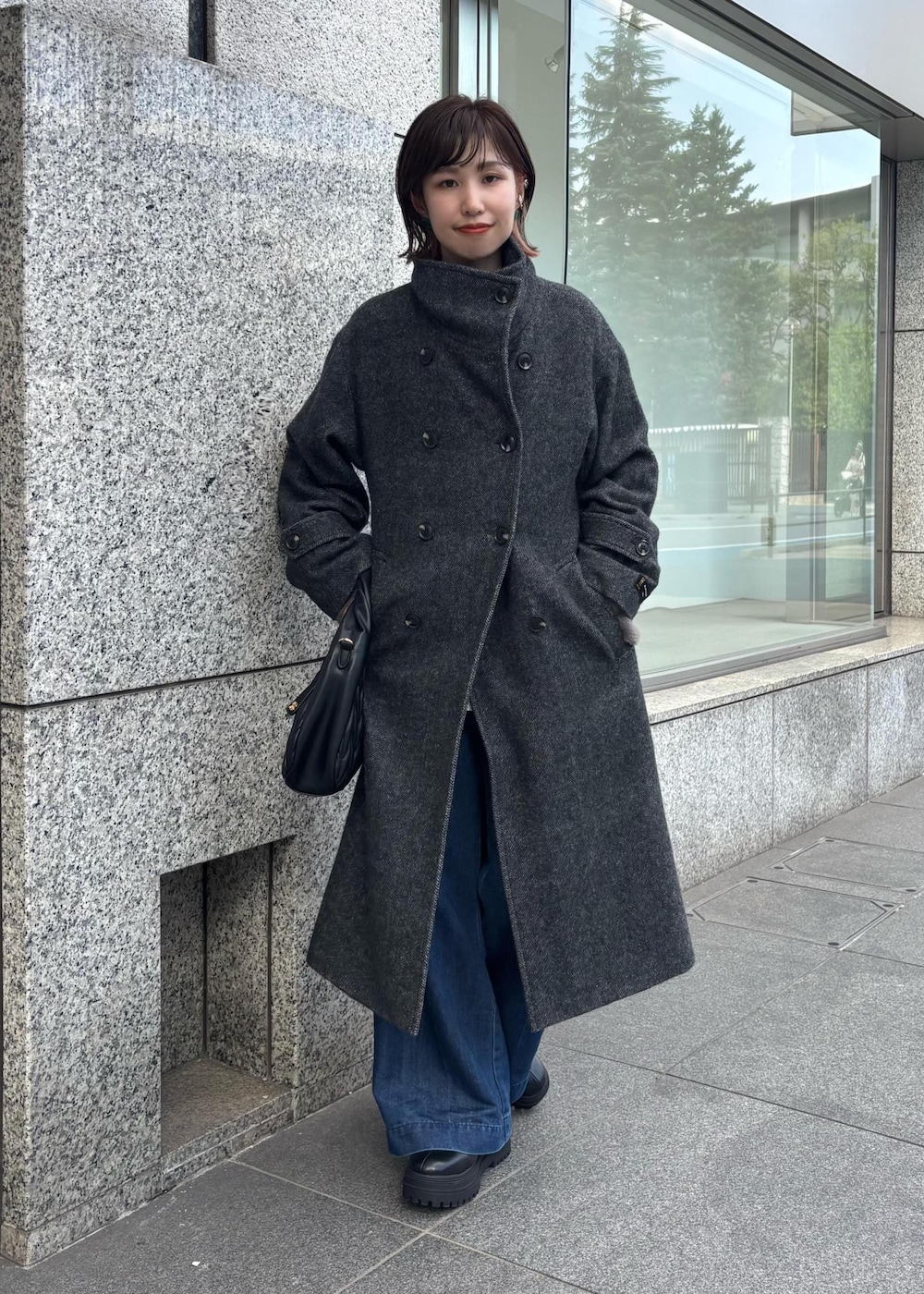 ブルー系のデニムパンツ、ブラック系のブーツ、ブラック系のハンドバッグを着用したレディースの秋コーディネートの8枚目の写真