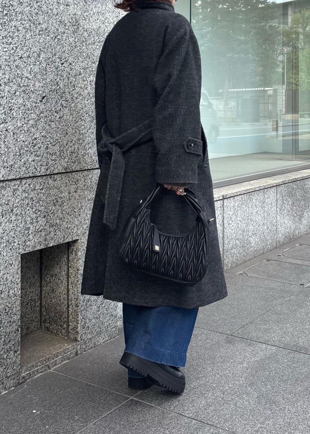 ブルー系のデニムパンツ、ブラック系のブーツ、ブラック系のハンドバッグを着用したレディースの秋コーディネートの5枚目の写真