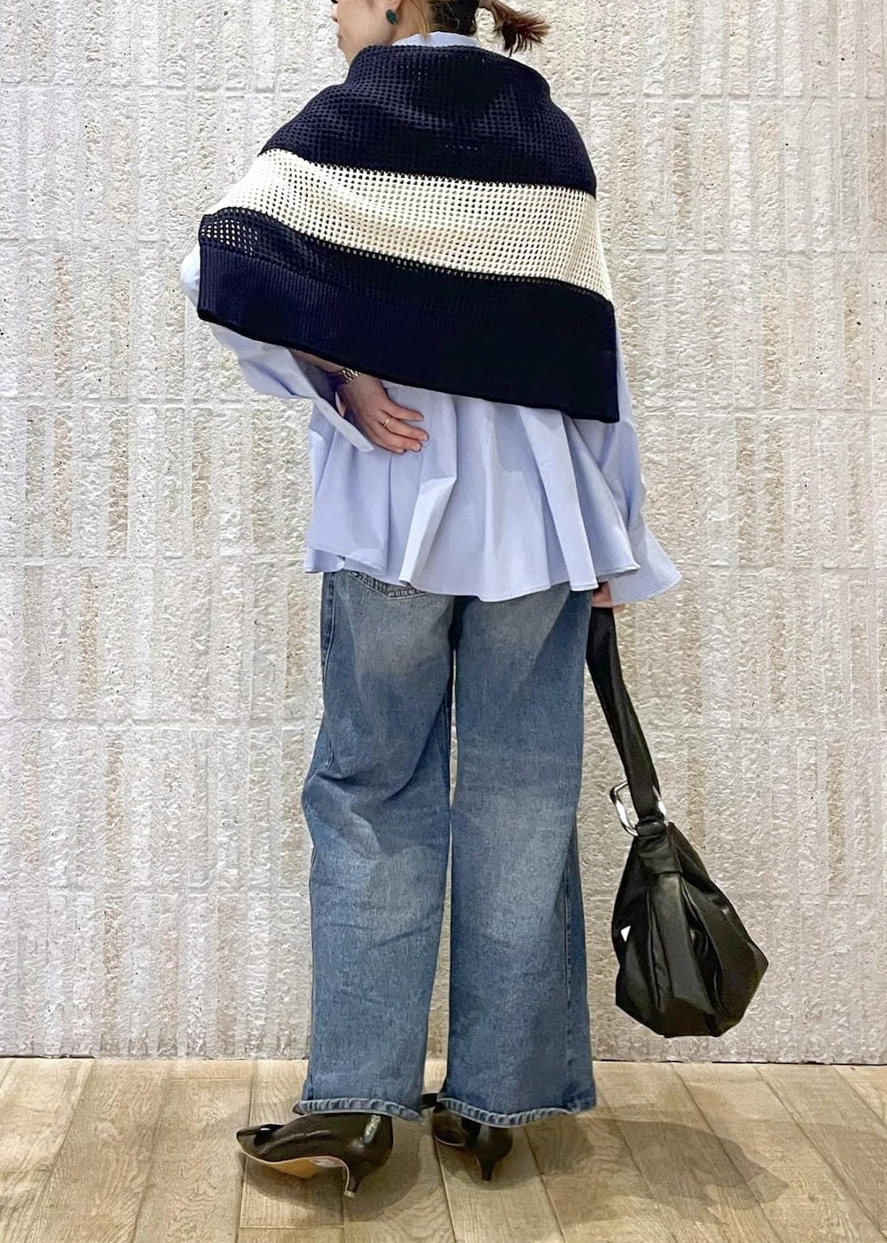 ブルー系のデニムパンツ、ブラック系のパンプス、ブラック系のハンドバッグを着用したレディースの春コーディネートの3枚目の写真