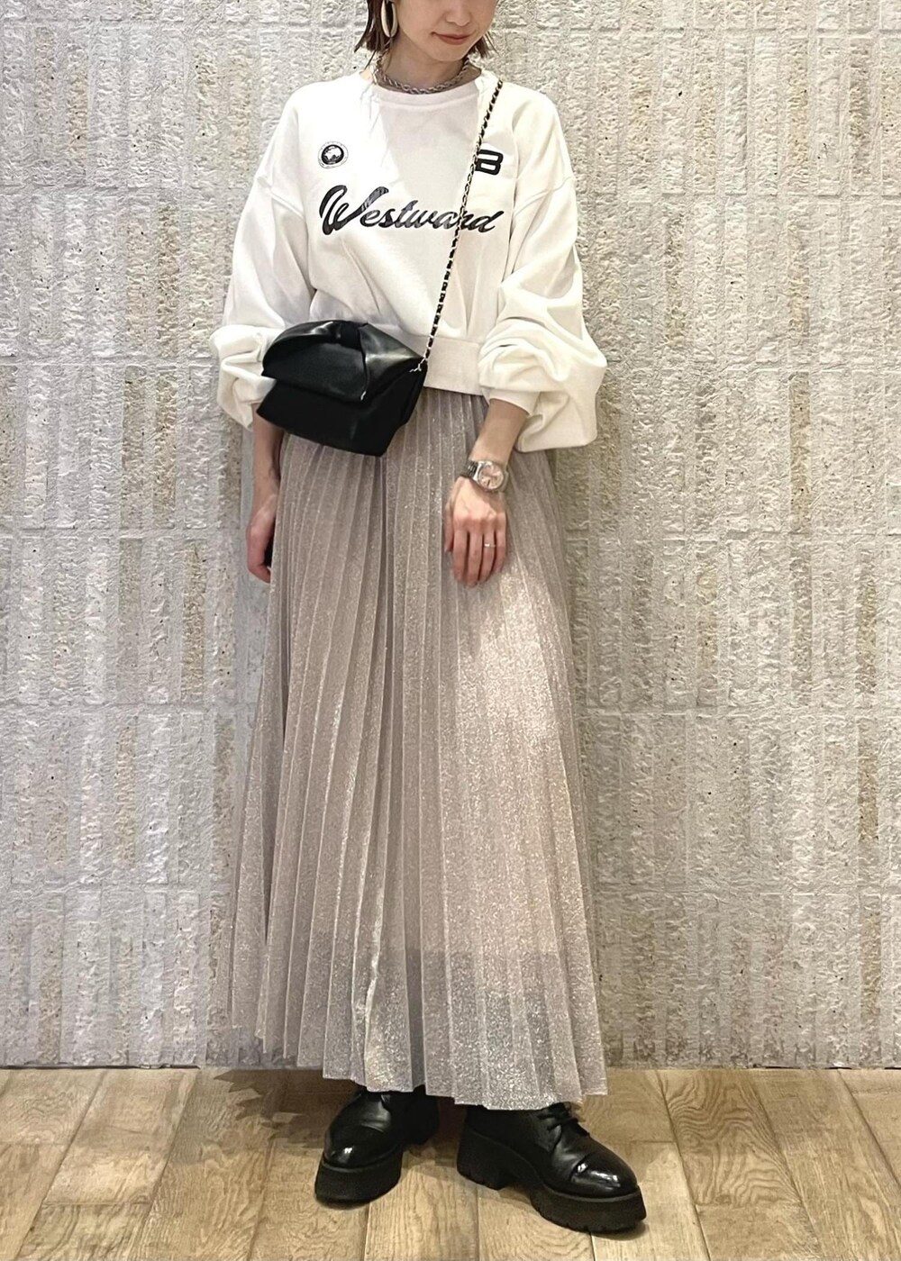 ブラック系のブーツ、シルバー系のスカート、ホワイト系のスウェットを着用したレディースの冬コーディネートの5枚目の写真