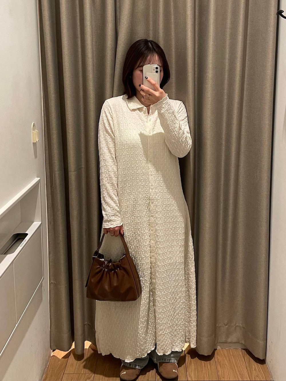 ブルー系のデニムパンツ、ホワイト系のワンピース、イエロー系のベルトを着用したレディースの春コーディネートの2枚目の写真