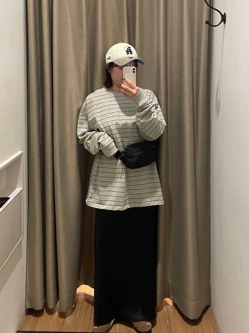 ブラック系のスカート、ブラック系のボディバッグ/ウエストポーチ、グレー系のTシャツ/カットソーを着用したレディースの春コーディネートの2枚目の写真