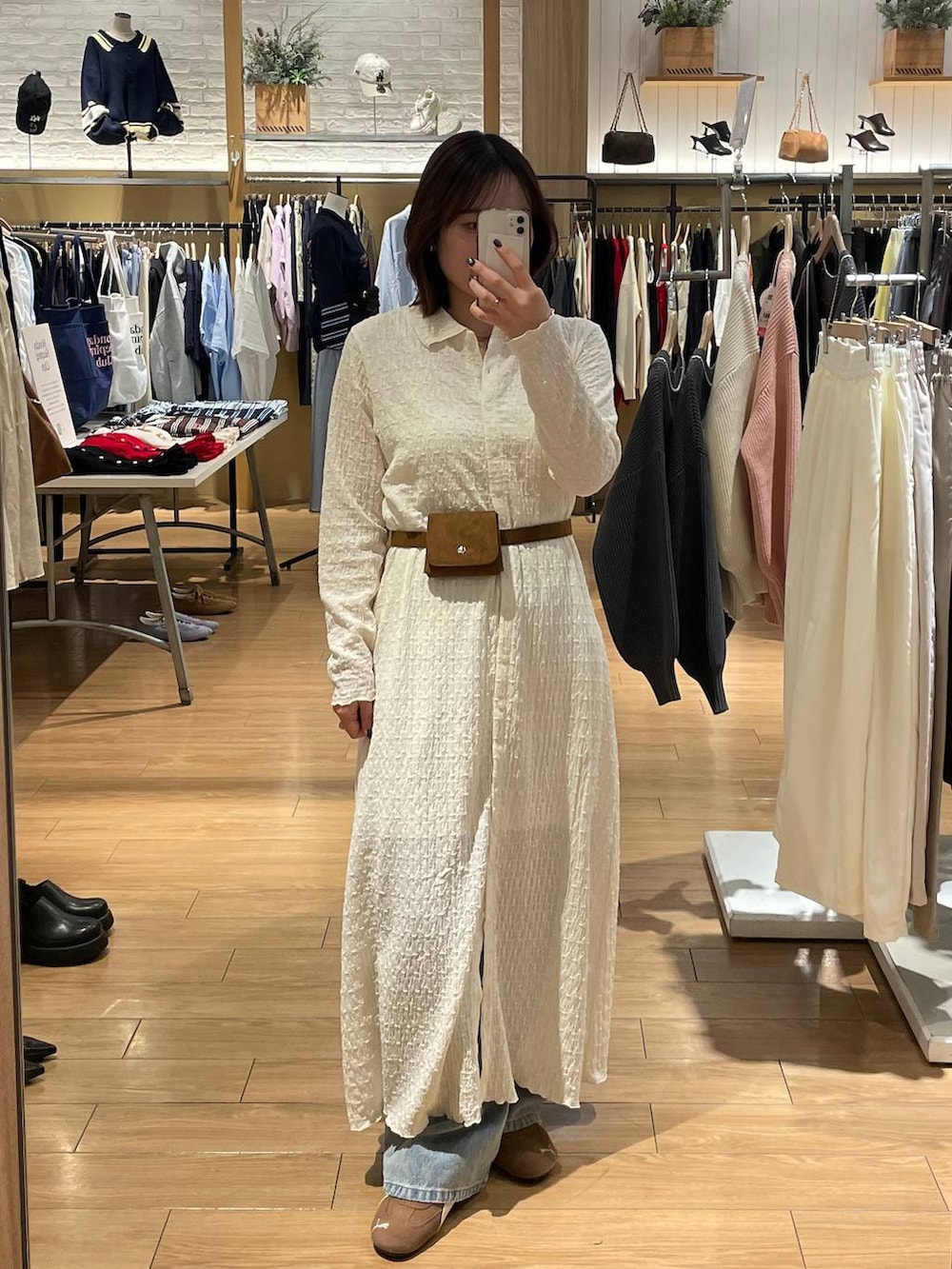 ブルー系のデニムパンツ、ホワイト系のワンピース、イエロー系のベルトを着用したレディースの春コーディネートの3枚目の写真