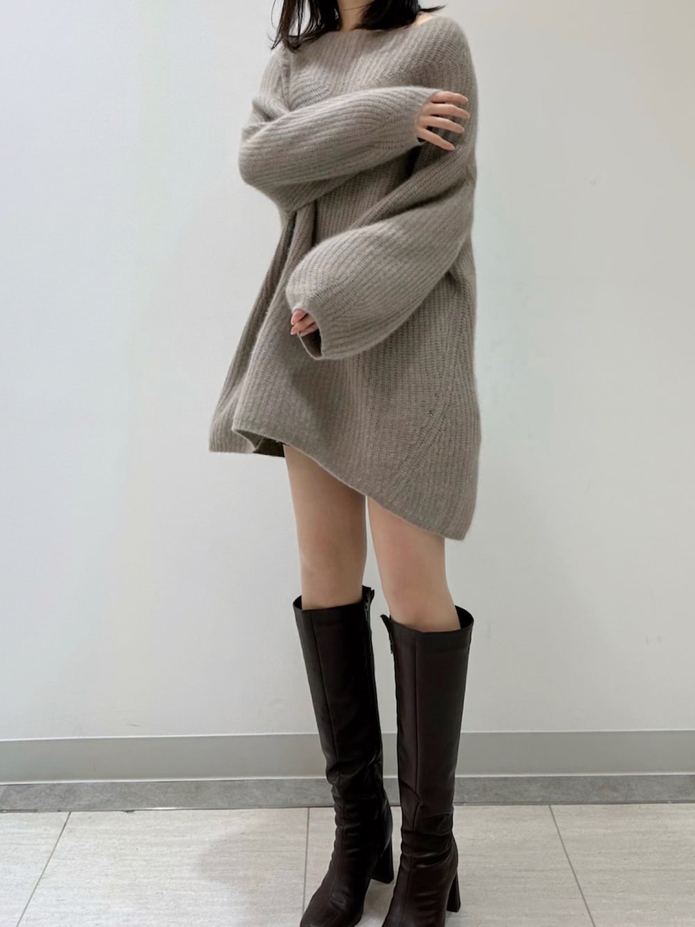 ホワイト系のワンピース、ベージュ系のハンドバッグ、ブラウン系のブーツを着用したレディースの冬コーディネートの2枚目の写真