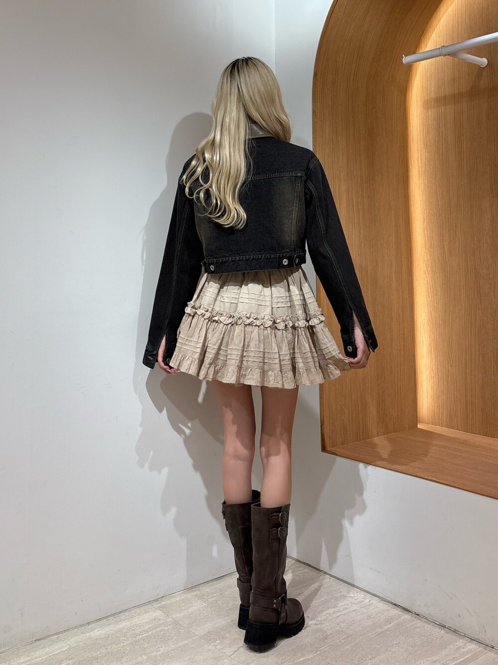 ベージュ系のスカート、ブラック系のデニムジャケット、ブラウン系のブーツを着用したレディースの夏コーディネートの3枚目の写真