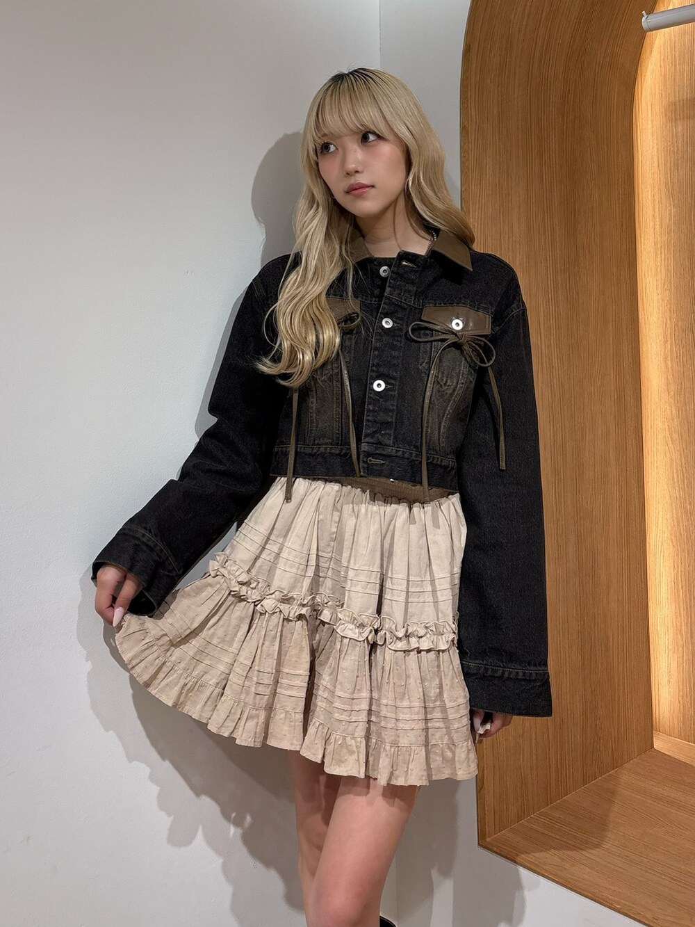 ベージュ系のスカート、ブラック系のデニムジャケット、ブラウン系のブーツを着用したレディースの夏コーディネートの4枚目の写真