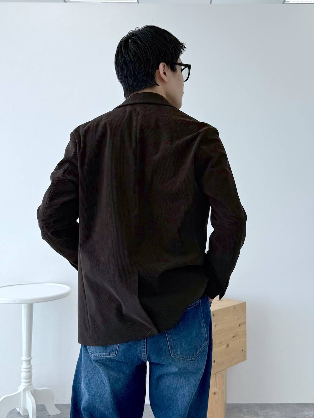 ブラック系のニット/セーター、ブラウン系のテーラードジャケット、ブルー系のデニムパンツを着用したメンズの秋コーディネートの8枚目の写真