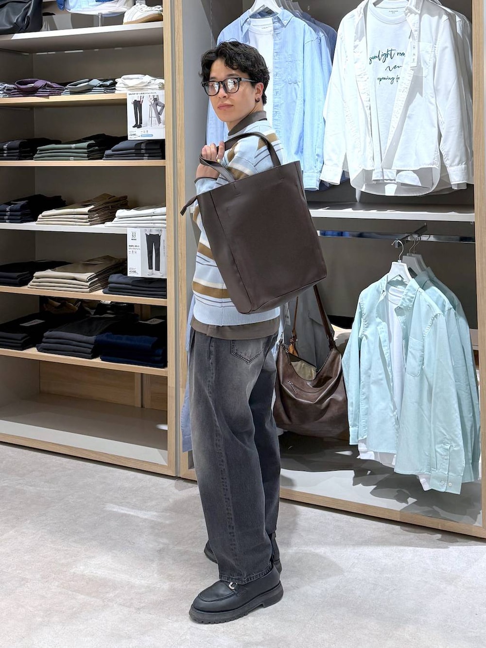 ブラック系のトートバッグ、ブルー系のニット/セーター、ブラウン系のシャツ/ブラウスを着用したメンズの春コーディネートの4枚目の写真