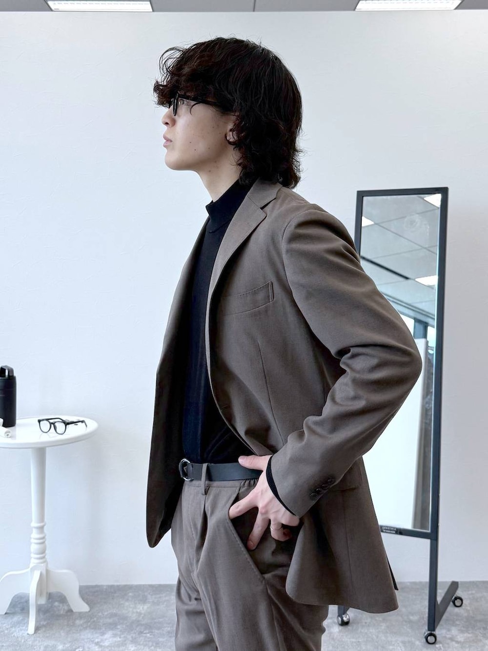 ブラウン系のテーラードジャケット、ブラウン系のスラックス、ブラック系のニット/セーターを着用したメンズの秋コーディネートの6枚目の写真