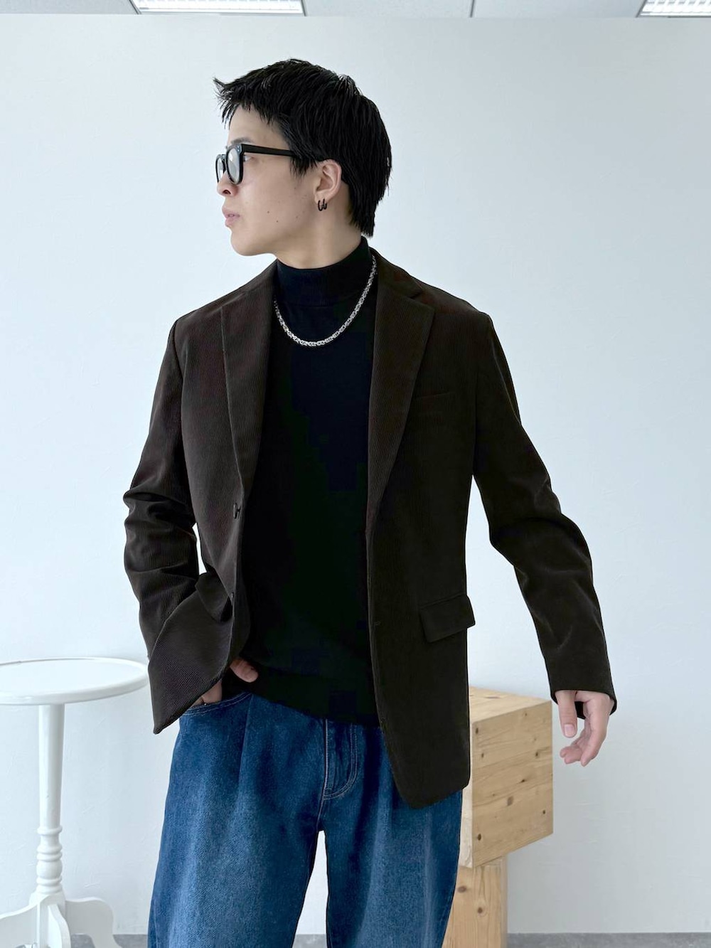 ブラック系のニット/セーター、ブラウン系のテーラードジャケット、ブルー系のデニムパンツを着用したメンズの秋コーディネートの6枚目の写真