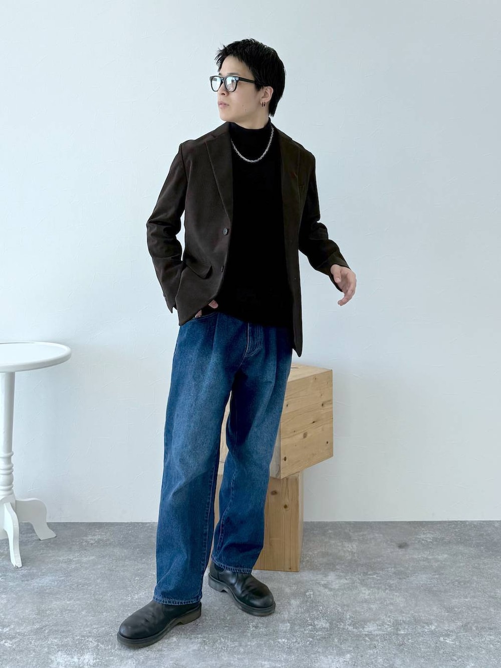 ブラック系のニット/セーター、ブラウン系のテーラードジャケット、ブルー系のデニムパンツを着用したメンズの秋コーディネートの3枚目の写真