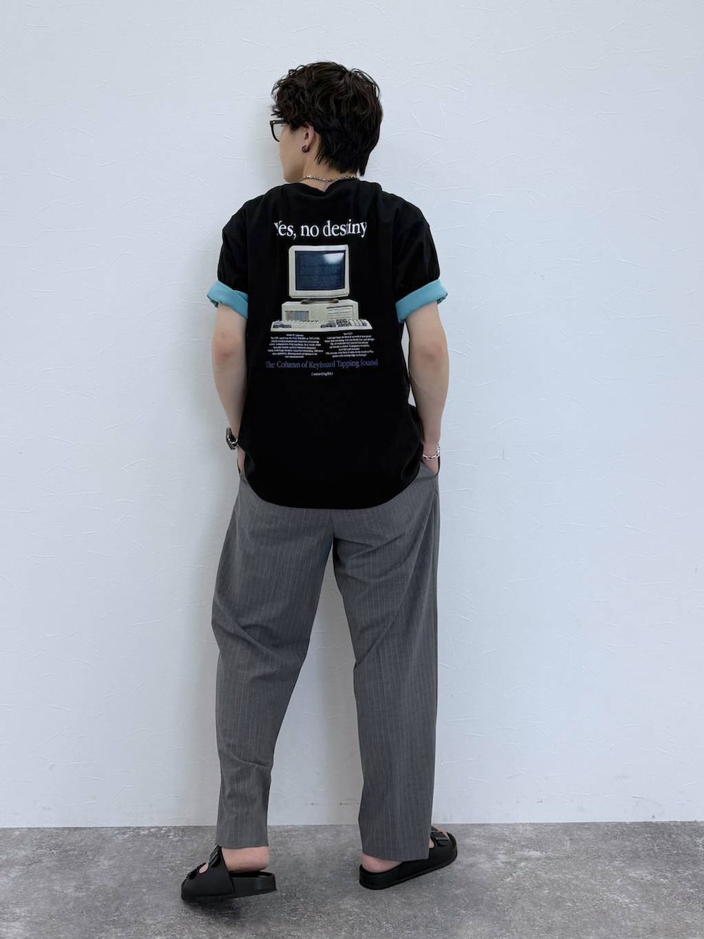グレー系のスラックス、ブルー系のTシャツ/カットソー、ブラック系のサンダルを着用したメンズの夏コーディネートの5枚目の写真