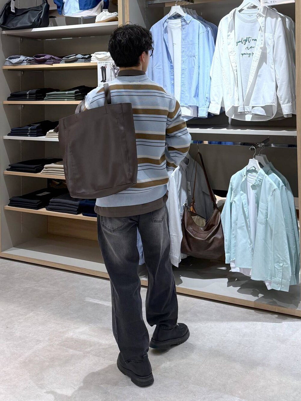 ブラック系のトートバッグ、ブルー系のニット/セーター、ブラウン系のシャツ/ブラウスを着用したメンズの春コーディネートの5枚目の写真