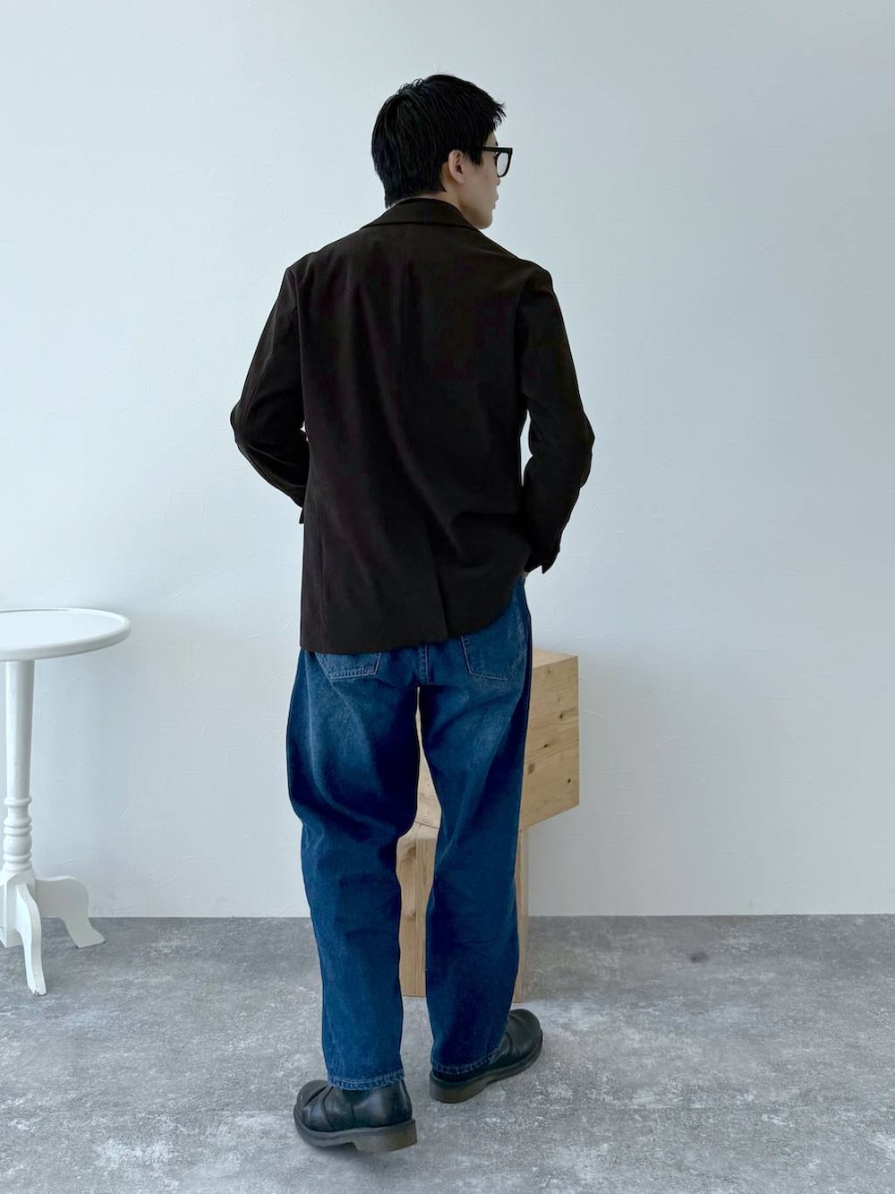 ブラック系のニット/セーター、ブラウン系のテーラードジャケット、ブルー系のデニムパンツを着用したメンズの秋コーディネートの5枚目の写真