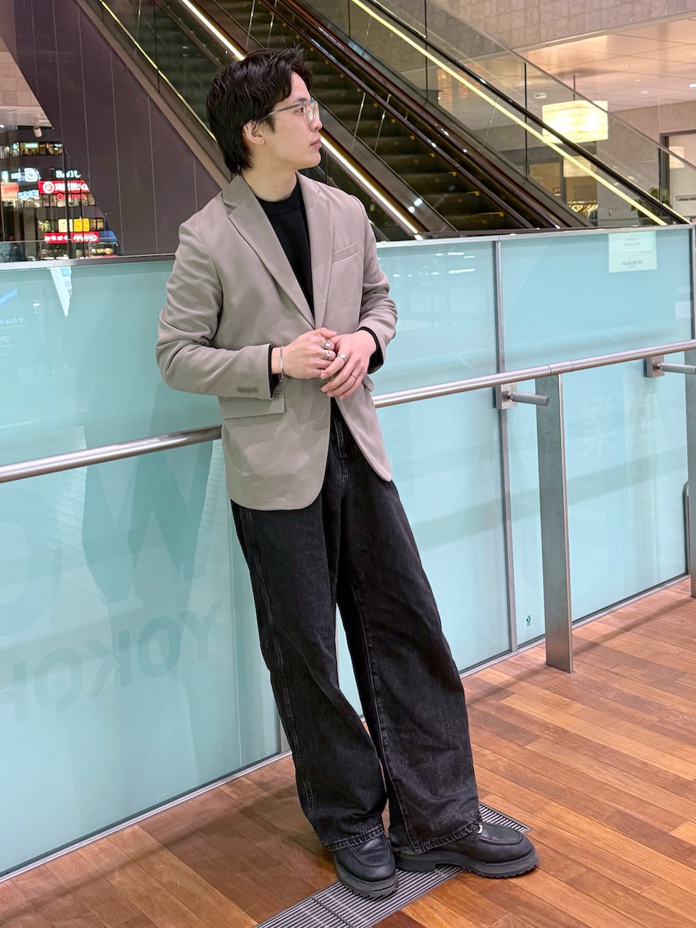 ブラック系のデニムパンツ、ブラック系のニット/セーター、ベージュ系のテーラードジャケットを着用したメンズの冬コーディネートの2枚目の写真