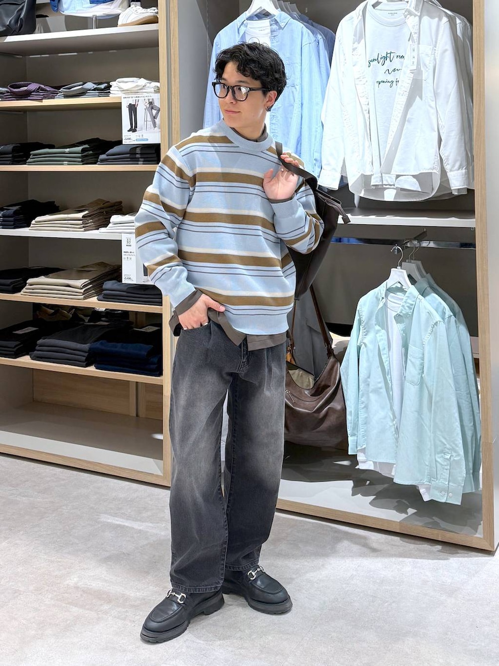 ブラック系のトートバッグ、ブルー系のニット/セーター、ブラウン系のシャツ/ブラウスを着用したメンズの春コーディネートの2枚目の写真