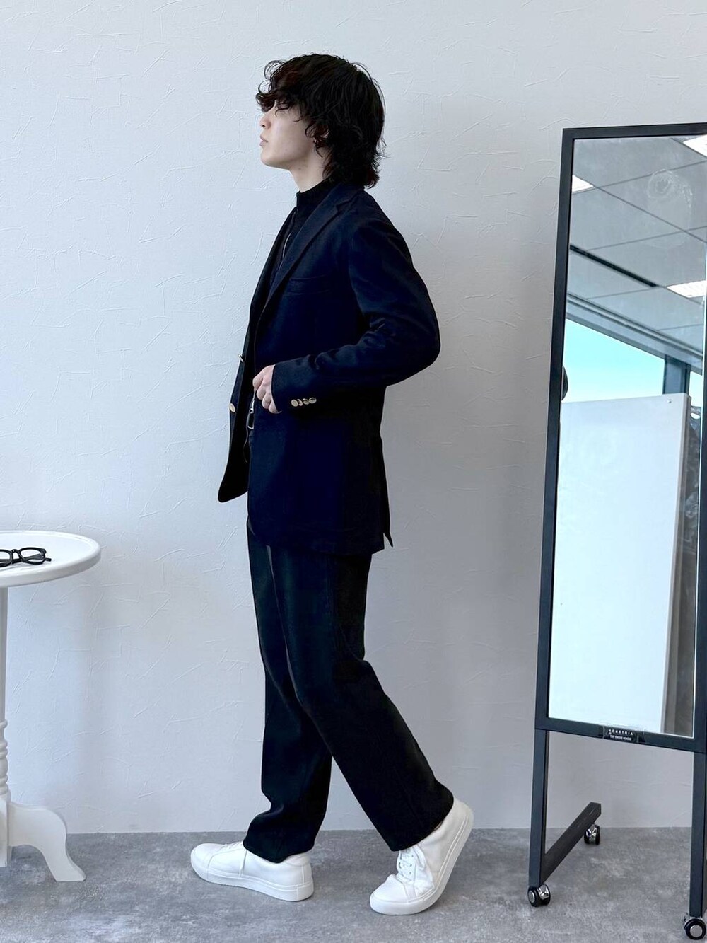 ブラック系のニット/セーター、ブルー系のテーラードジャケット、ブラック系のスラックスを着用したメンズの秋コーディネートの3枚目の写真