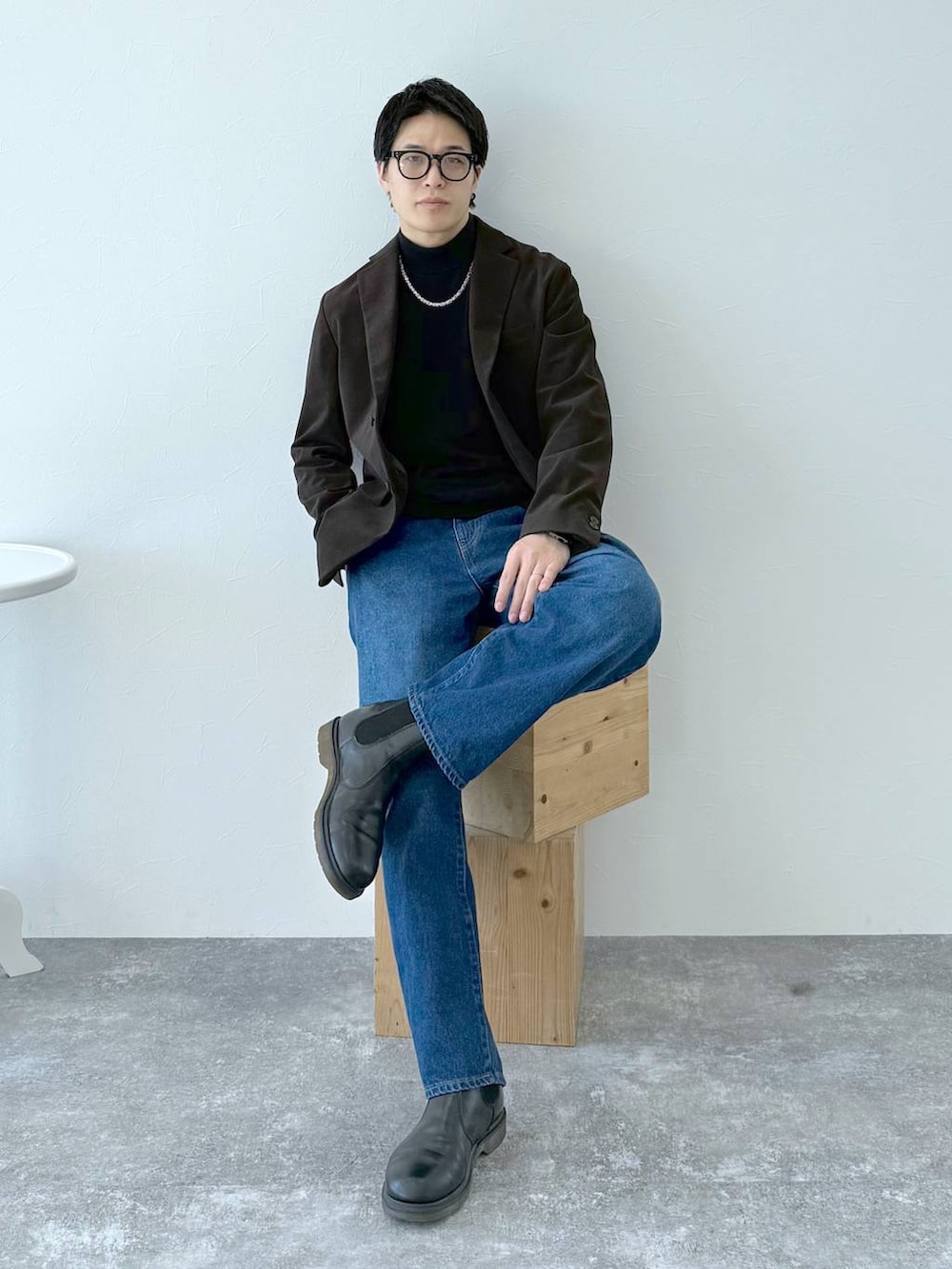 ブラック系のニット/セーター、ブラウン系のテーラードジャケット、ブルー系のデニムパンツを着用したメンズの秋コーディネートの2枚目の写真