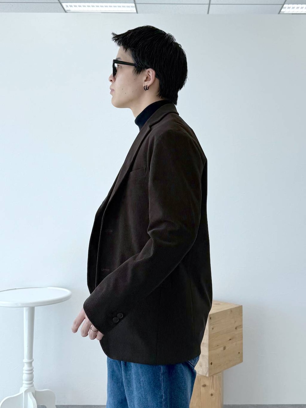 ブラック系のニット/セーター、ブラウン系のテーラードジャケット、ブルー系のデニムパンツを着用したメンズの秋コーディネートの7枚目の写真