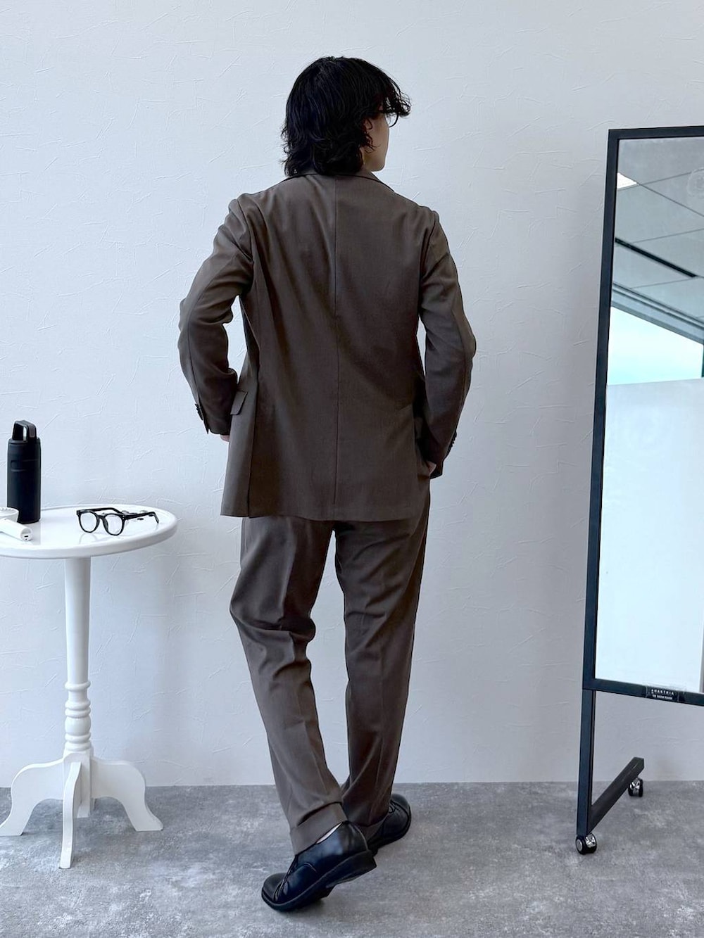 ブラウン系のテーラードジャケット、ブラウン系のスラックス、ブラック系のニット/セーターを着用したメンズの秋コーディネートの4枚目の写真