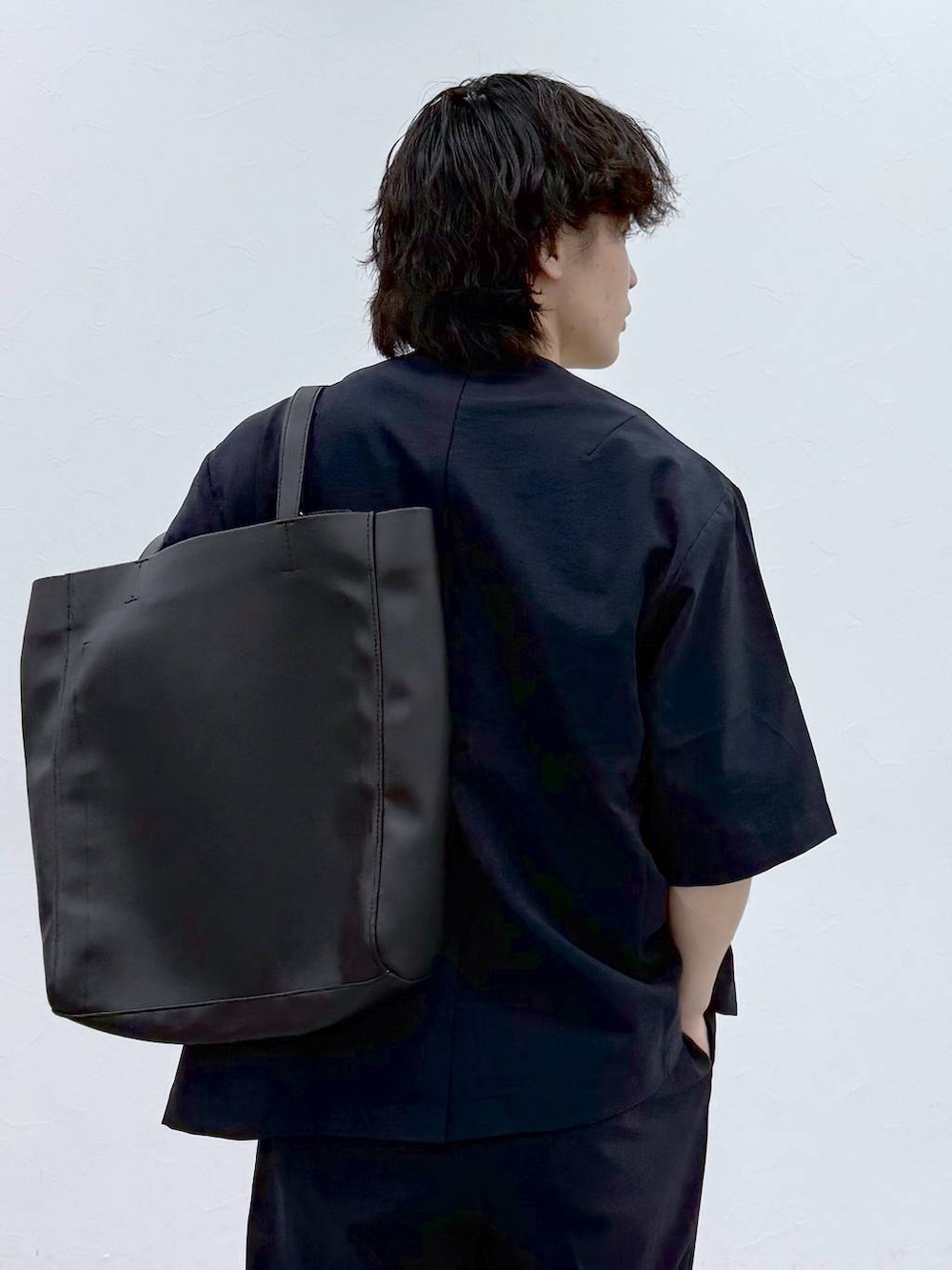 ブラック系のトートバッグ、ホワイト系のTシャツ/カットソー、ブルー系のノーカラージャケットを着用したメンズの春コーディネートの7枚目の写真