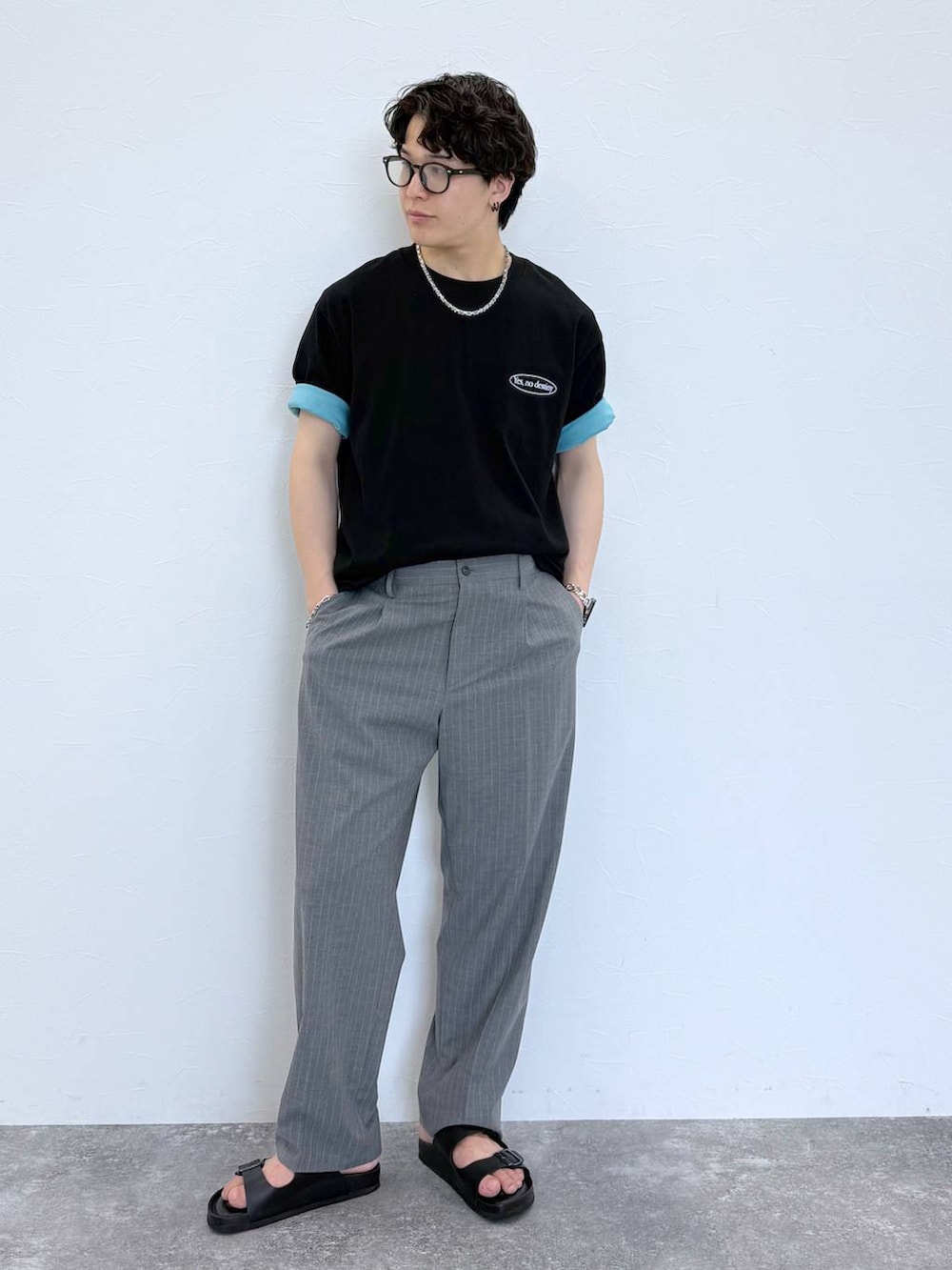 グレー系のスラックス、ブルー系のTシャツ/カットソー、ブラック系のサンダルを着用したメンズの夏コーディネートの3枚目の写真