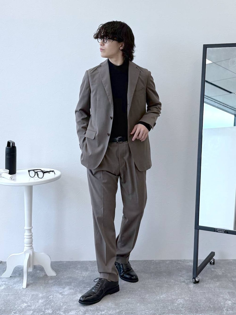 ブラウン系のテーラードジャケット、ブラウン系のスラックス、ブラック系のニット/セーターを着用したメンズの秋コーディネートの2枚目の写真