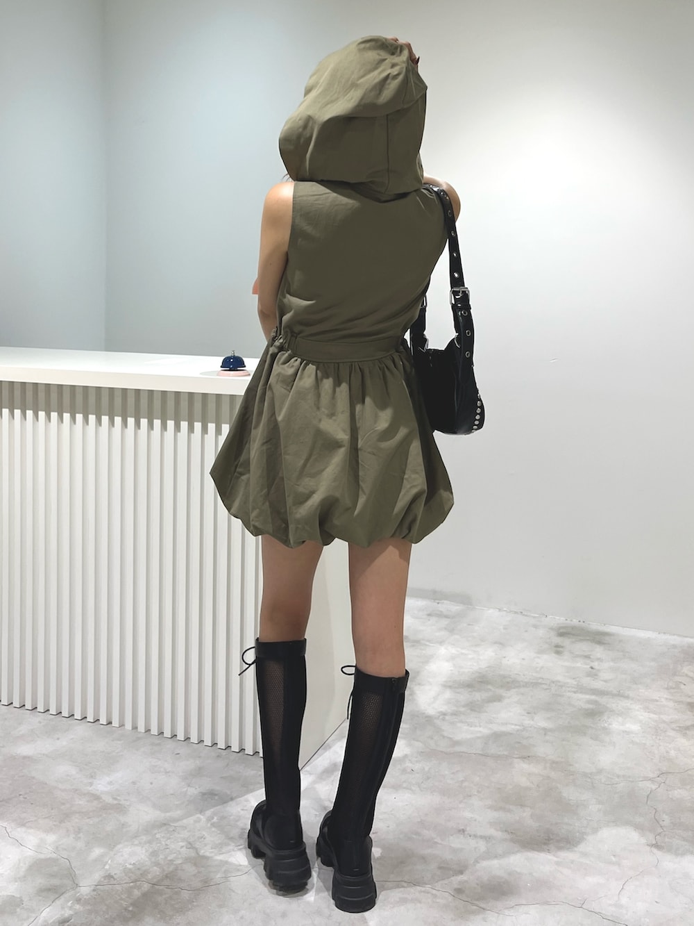 グリーン系のワンピース、ブラック系のブーツを着用したレディースの春コーディネートの2枚目の写真