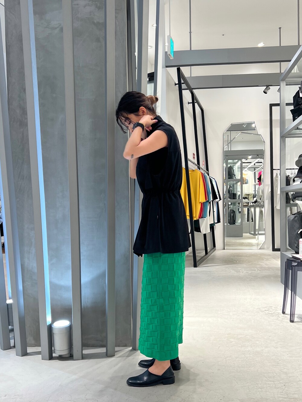 ブラック系のパンプス、グリーン系のスカート、ブラック系のベストを着用したレディースの夏コーディネートの3枚目の写真