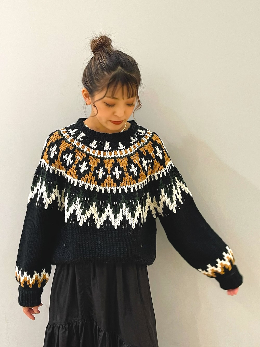 ブラック系のニット/セーター、ブラック系のスカート、ブラック系のブーツを着用したレディースの秋コーディネートの2枚目の写真