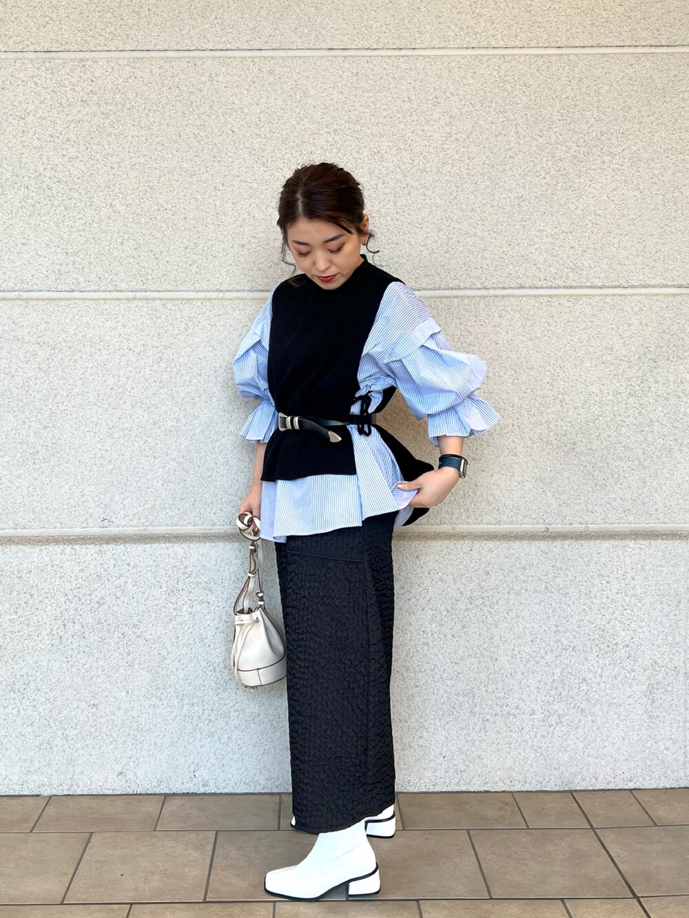 ホワイト系のショルダーバッグ、ブルー系のシャツ/ブラウス、ブラック系のベストを着用したレディースの冬コーディネートの2枚目の写真