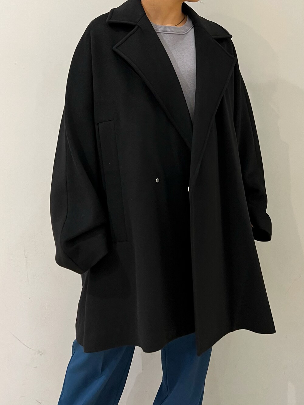 グレー系のニット/セーター、ブラック系のチェスターコート、ブルー系のスラックスを着用したレディースの冬コーディネートの3枚目の写真