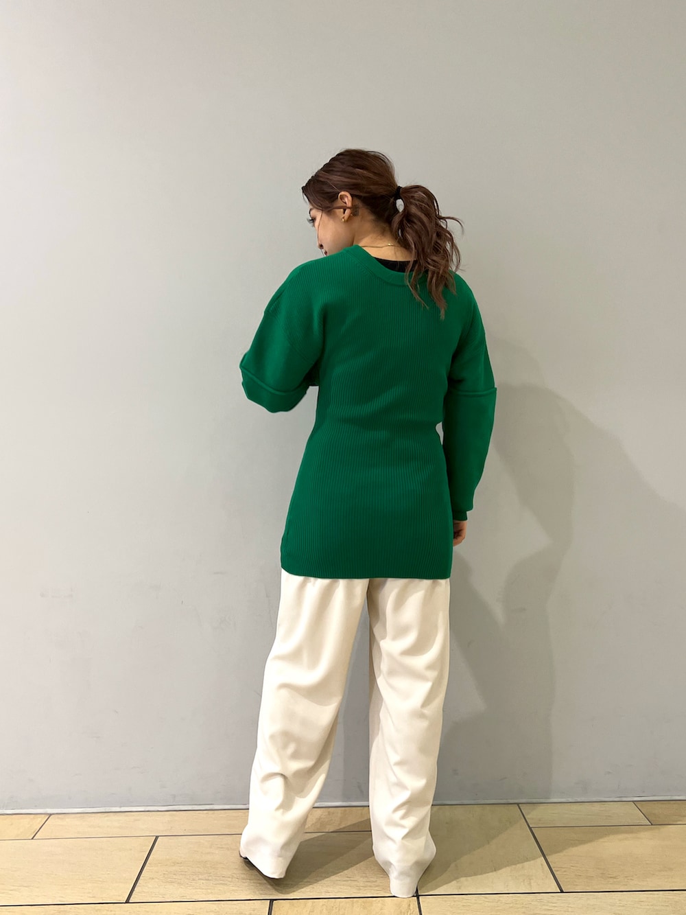 グリーン系のトップス、ホワイト系のパンツ、ホワイト系のブーツを着用したレディースの冬コーディネートの3枚目の写真