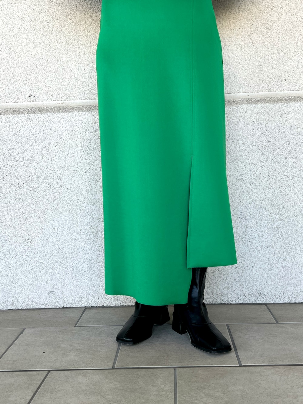 グリーン系のスカート、ブラック系のTシャツ/カットソー、ブラック系のブーツを着用したレディースの冬コーディネートの3枚目の写真