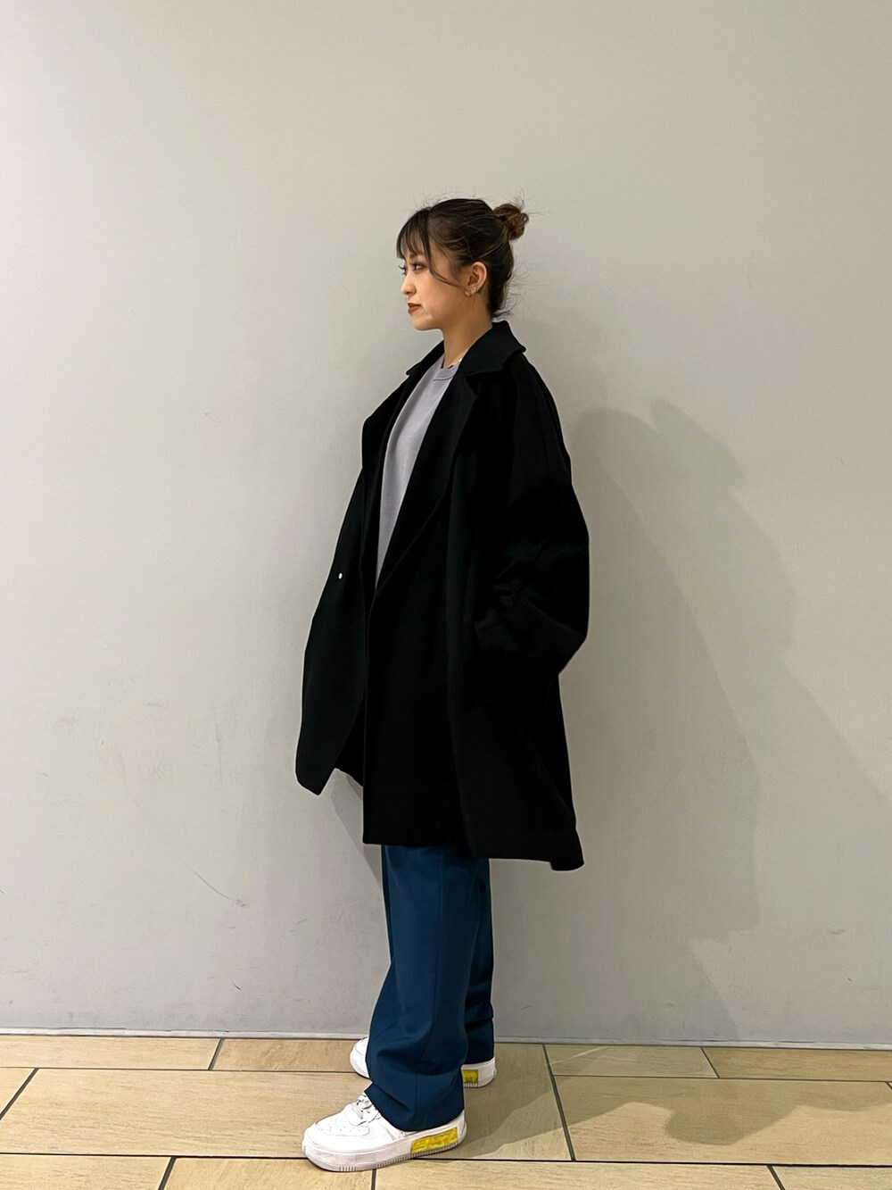 グレー系のニット/セーター、ブラック系のチェスターコート、ブルー系のスラックスを着用したレディースの冬コーディネートの2枚目の写真