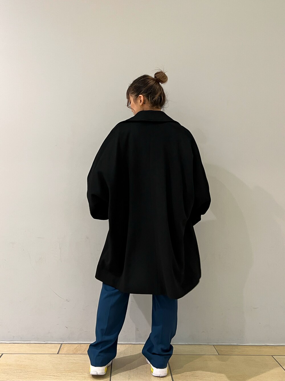 グレー系のニット/セーター、ブラック系のチェスターコート、ブルー系のスラックスを着用したレディースの冬コーディネートの4枚目の写真