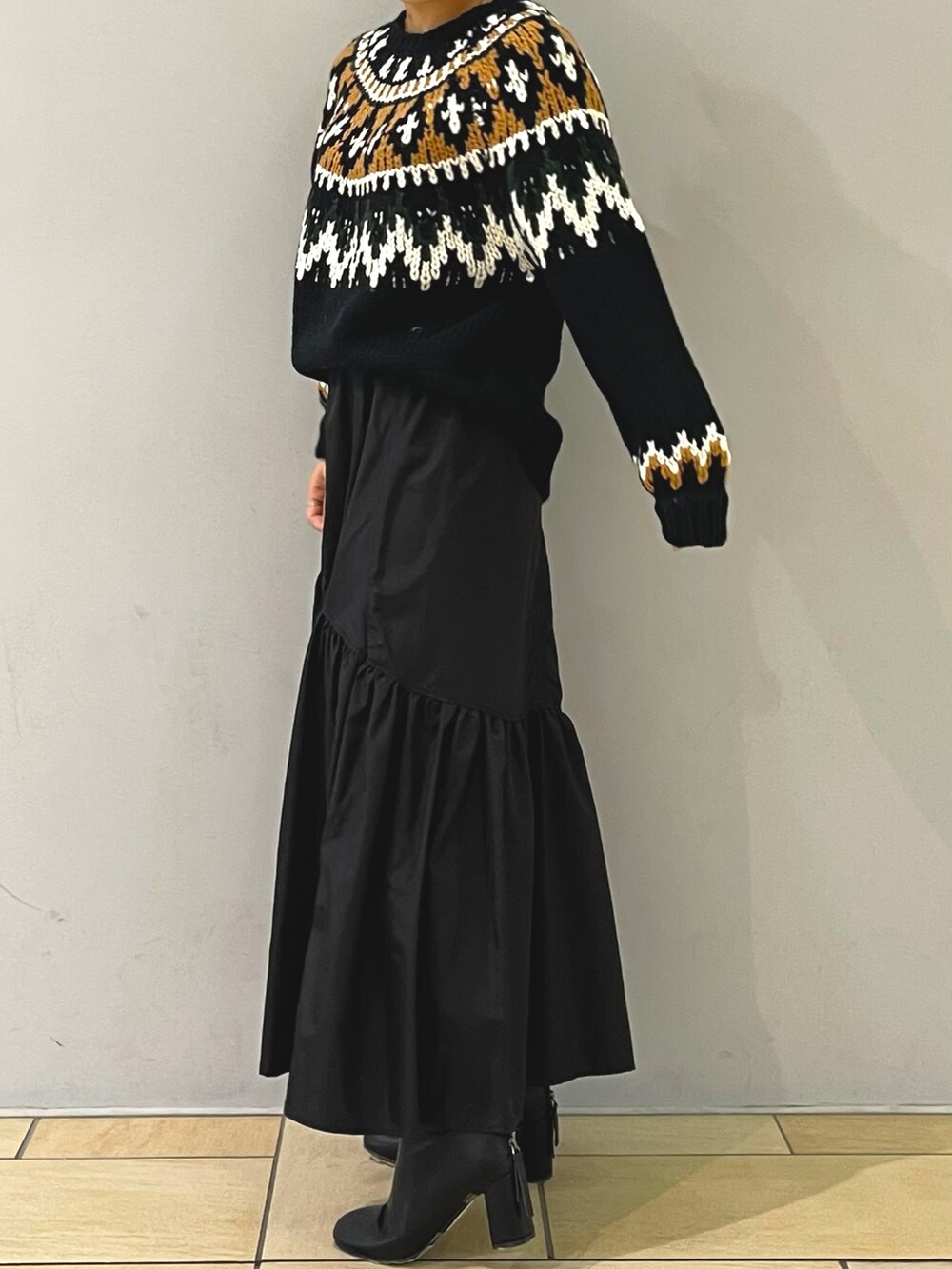 ブラック系のニット/セーター、ブラック系のスカート、ブラック系のブーツを着用したレディースの秋コーディネートの4枚目の写真