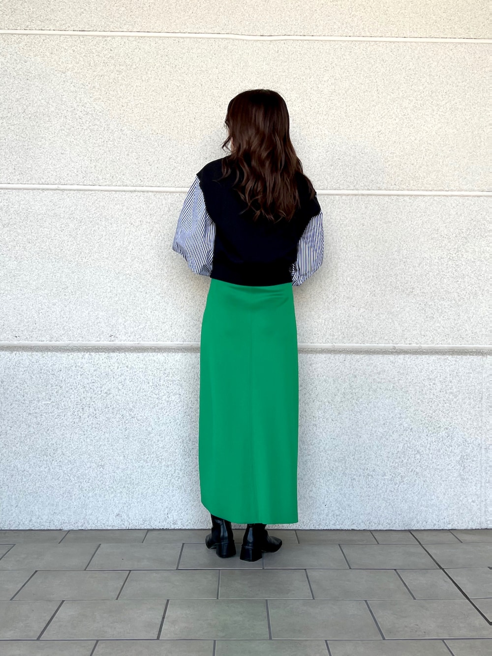 グリーン系のスカート、ブラック系のTシャツ/カットソー、ブラック系のブーツを着用したレディースの冬コーディネートの2枚目の写真