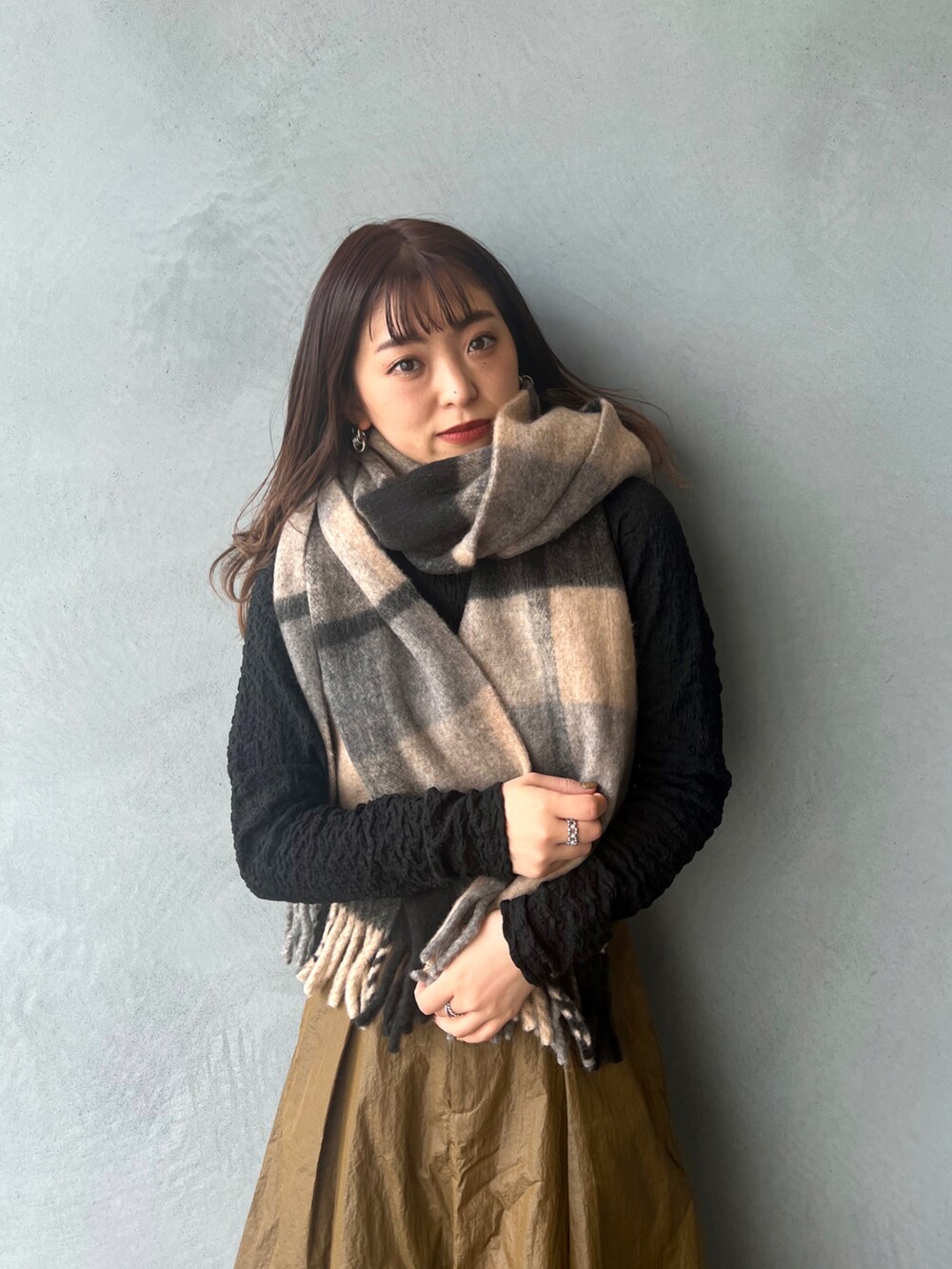 ブラック系のTシャツ/カットソー、グリーン系のスカート、グレー系のマフラーを着用したレディースの冬コーディネートの2枚目の写真