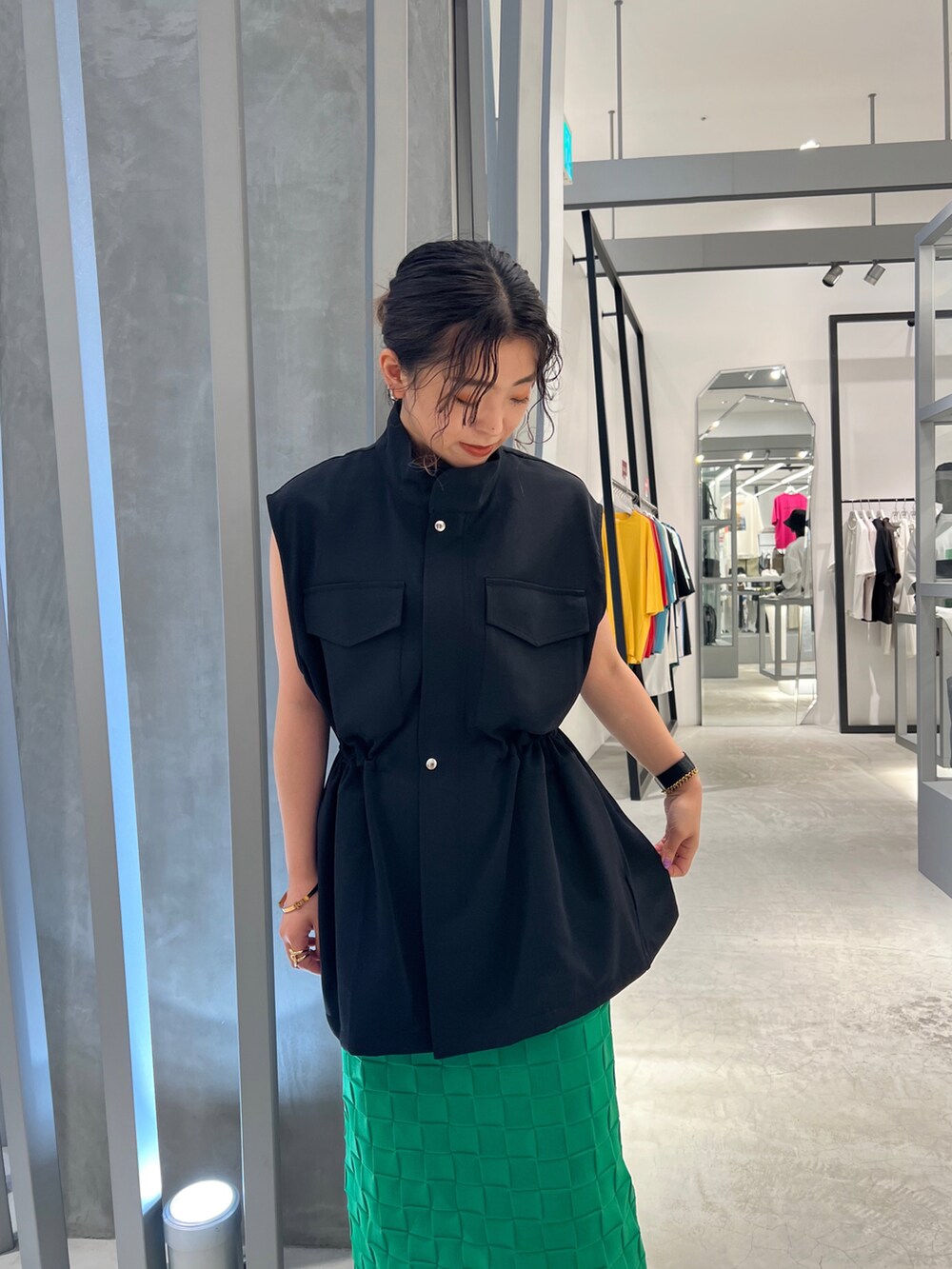 ブラック系のパンプス、グリーン系のスカート、ブラック系のベストを着用したレディースの夏コーディネートの4枚目の写真