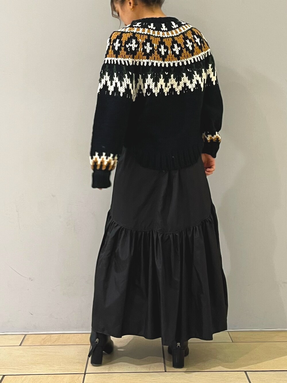 ブラック系のニット/セーター、ブラック系のスカート、ブラック系のブーツを着用したレディースの秋コーディネートの3枚目の写真