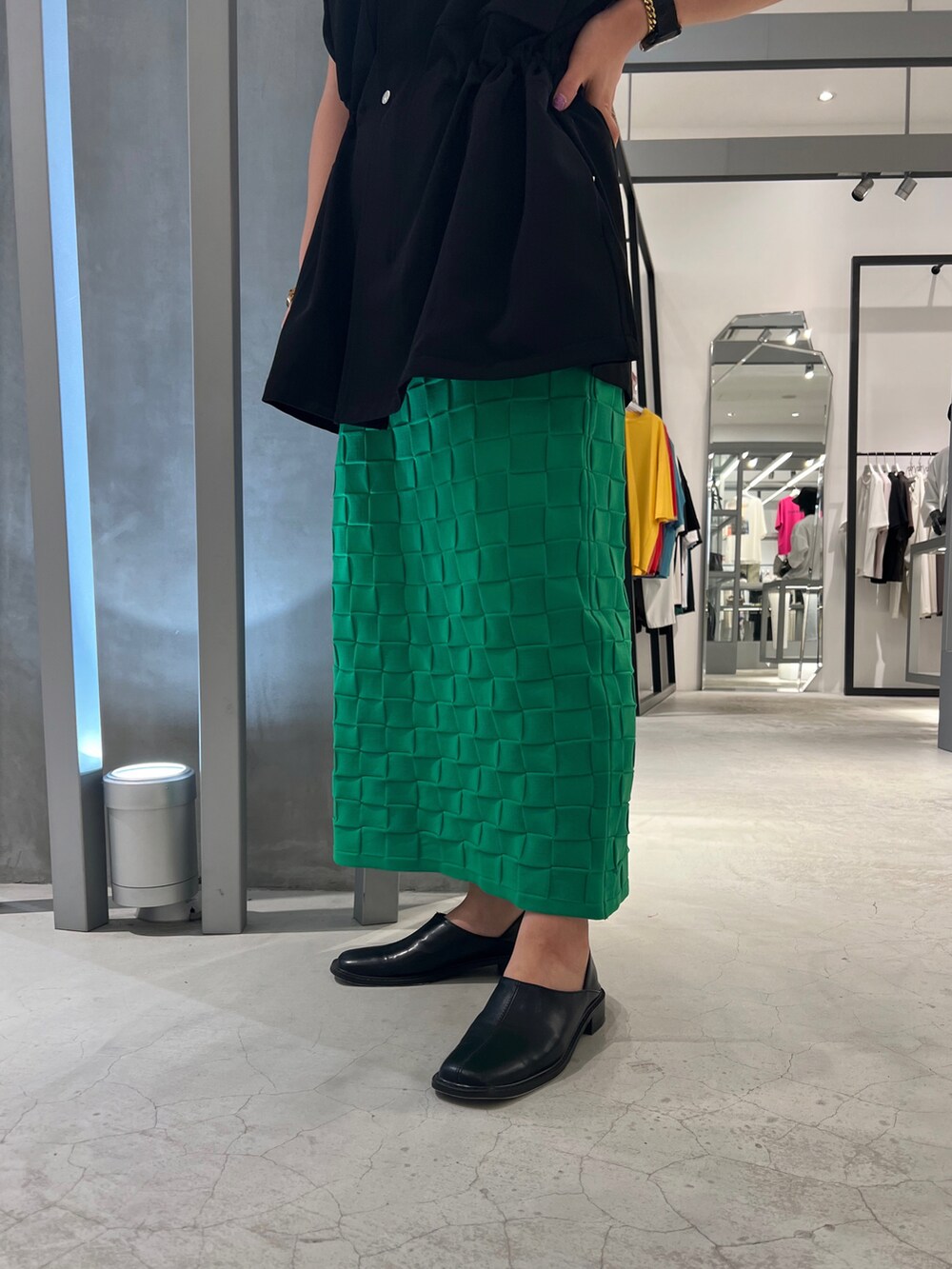 ブラック系のパンプス、グリーン系のスカート、ブラック系のベストを着用したレディースの夏コーディネートの5枚目の写真