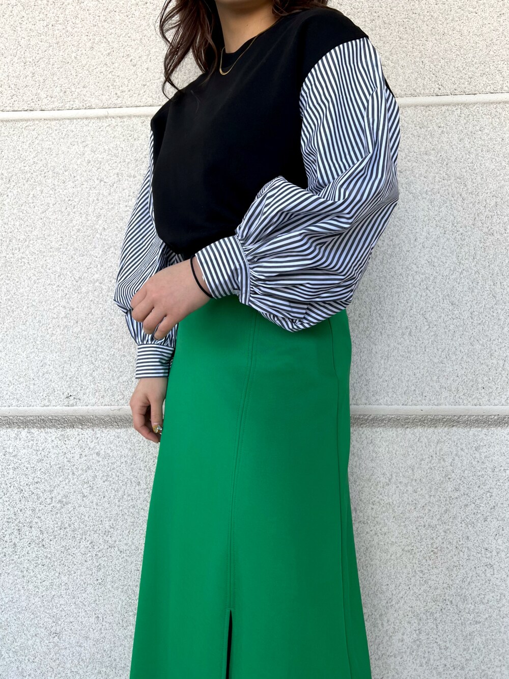 グリーン系のスカート、ブラック系のTシャツ/カットソー、ブラック系のブーツを着用したレディースの冬コーディネートの4枚目の写真