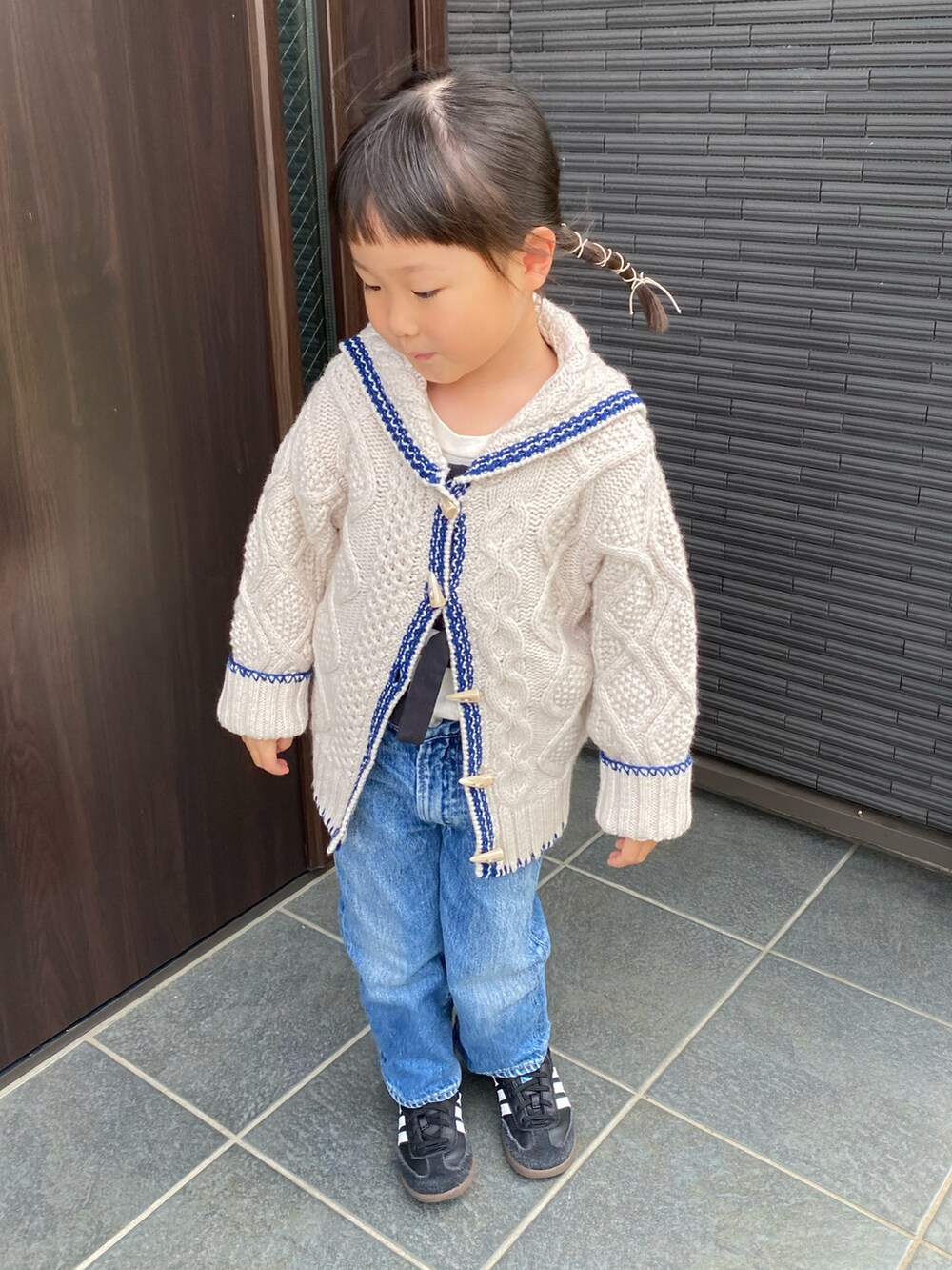 ベージュ系のニット/セーター、ブルー系のデニムパンツ、ブラック系のスニーカーを着用したキッズの秋コーディネートの2枚目の写真