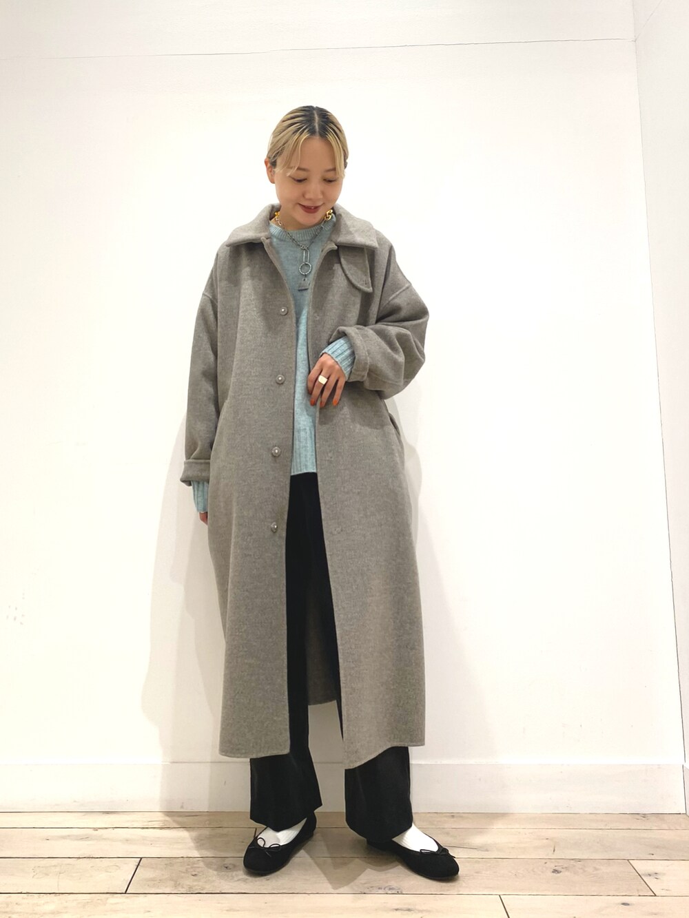 グリーン系のニット/セーター、グレー系のステンカラーコート、ブラック系のバレエシューズを着用したレディースの秋コーディネートの3枚目の写真