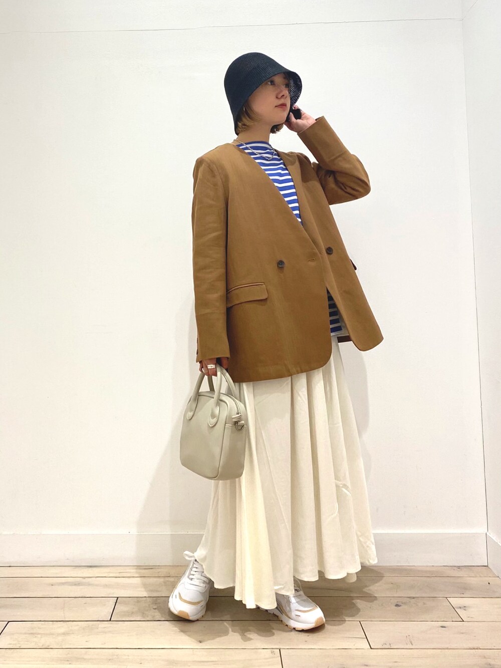 ブルー系のTシャツ/カットソー、ベージュ系のノーカラージャケット、ホワイト系のスカートを着用したレディースの春コーディネートの2枚目の写真